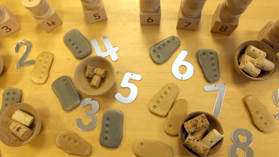 A set of educational counting blocks and number shapes used in teaching activities for children, highlighting help with childcare costs options.