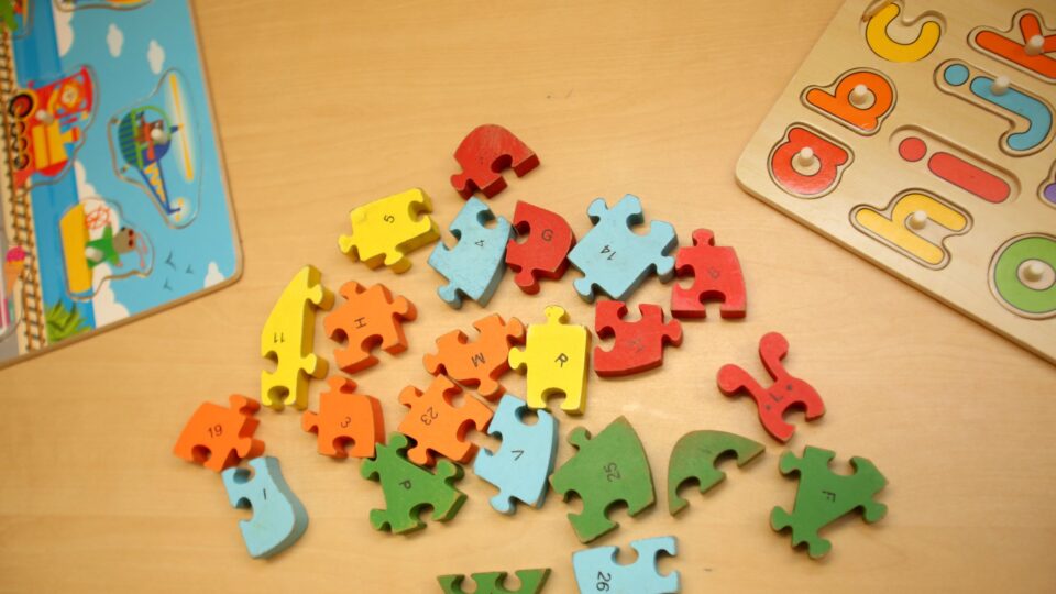 Colourful wooden puzzle pieces and alphabet board, showcasing engaging nursery resources for early learning.